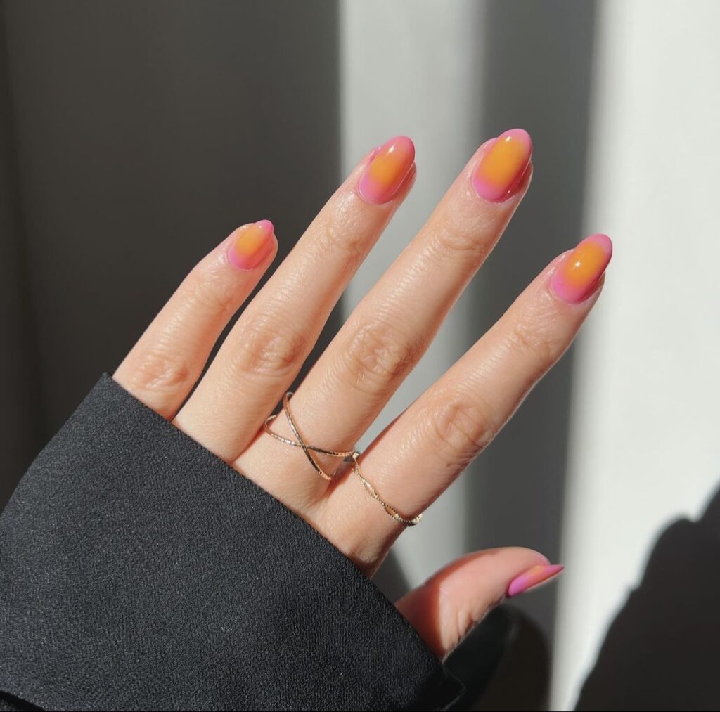 The photograph captures nails with an orange to pink gradient, reminiscent of a summertime fruit sorbet.