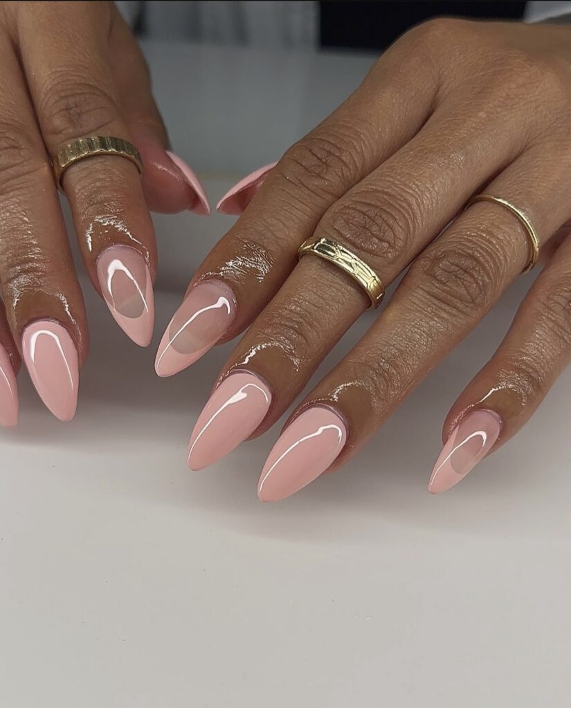  A picture of a hand adorned with classic almond-shaped blush-colored nails, exuding a timeless summer elegance.