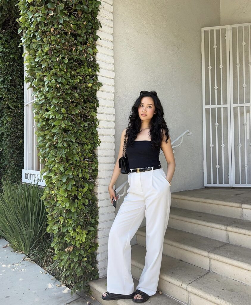 White wide-leg pants paired with a black strapless top, complemented by a black belt and matching handbag. Ideal for city outings, this outfit is both stylish and comfortable.