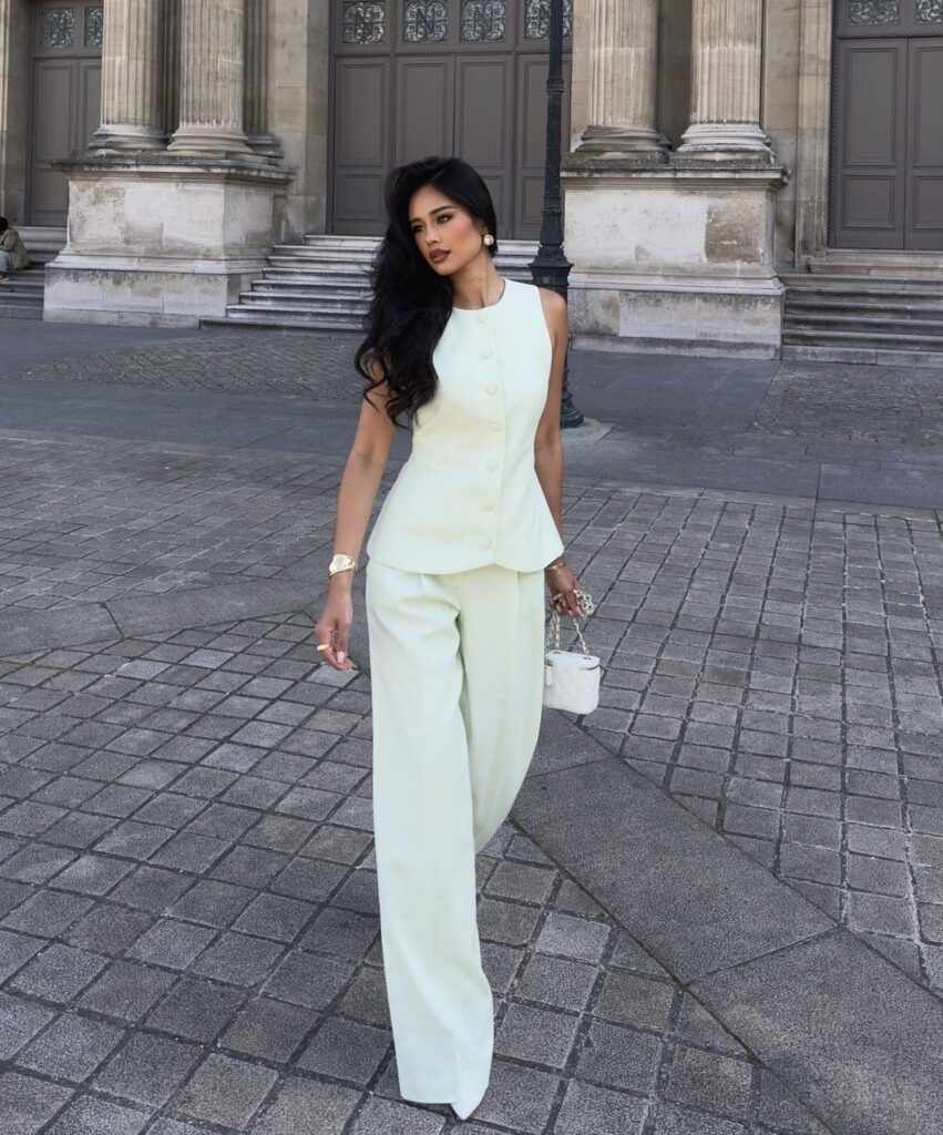 A sleeveless top matched with wide-leg pants creating a monochrome look. A white purse and neutral accessories complete this elegant outfit.