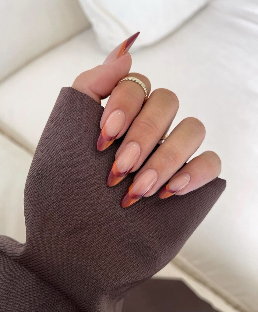 Autumn ombre nails with shades of red, orange, and yellow blending together.