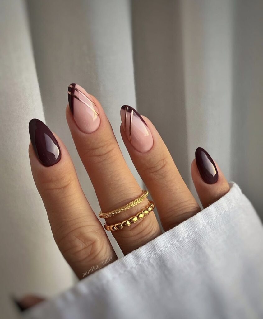 Burgundy nails with gold stripes.