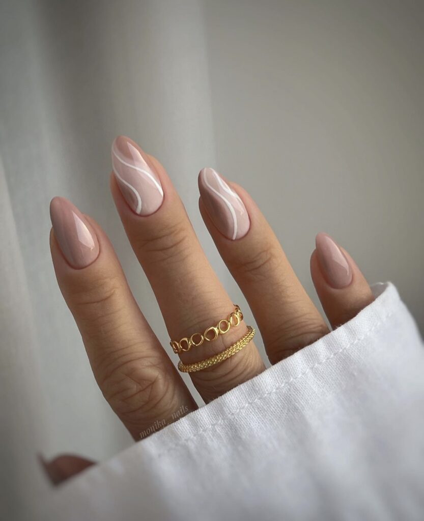 Light beige nails with white swirl accents.