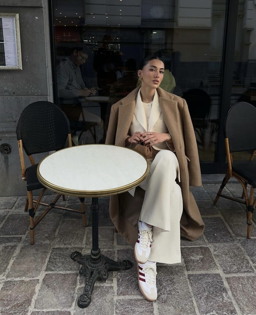 A classic beige trench coat paired with white trousers and sneakers.