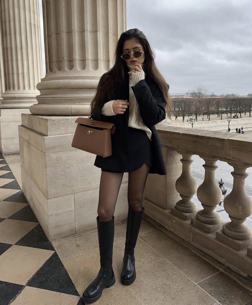 An elegant black skirt paired with black boots and a brown bag.