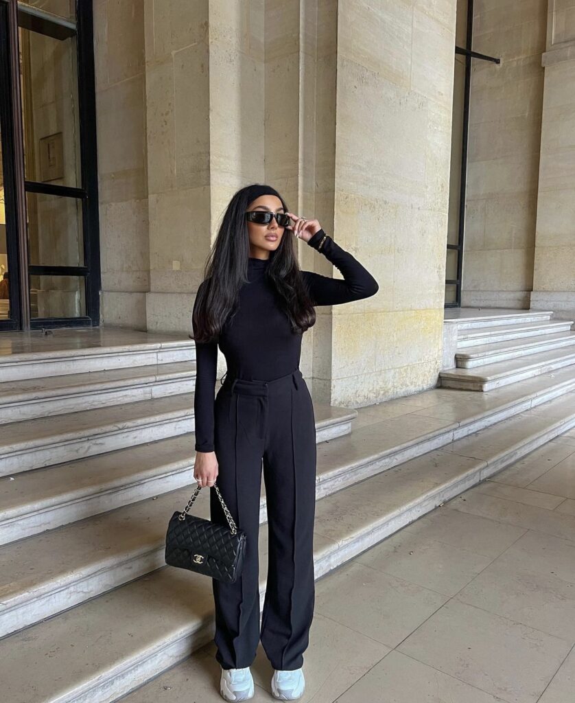 A classic black turtleneck top with black trousers, and a black handbag.