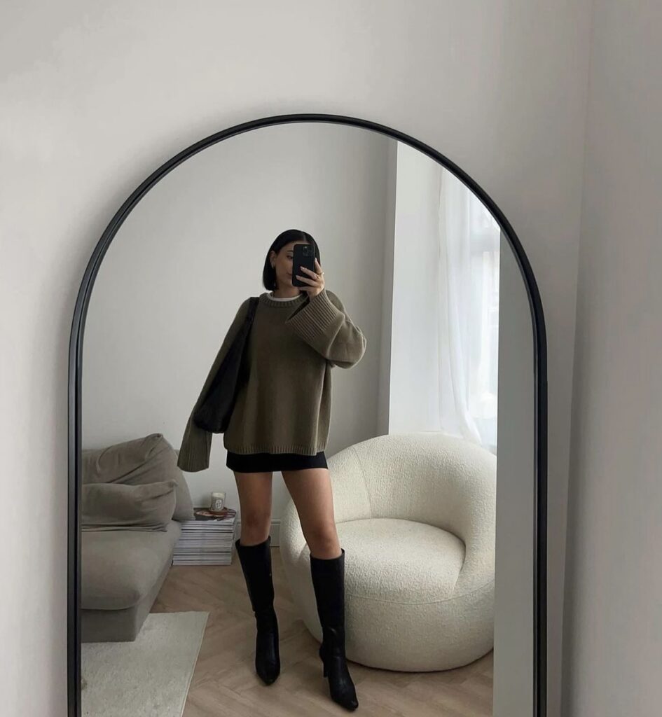 Knee-high boots paired with a sweater and a black skirt.