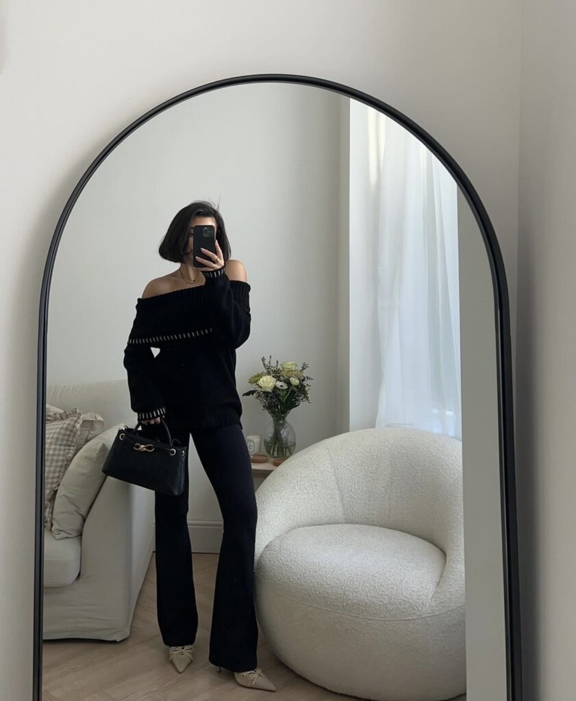 Flared leggings paired with a black off shoulder sweater and a black handbag.