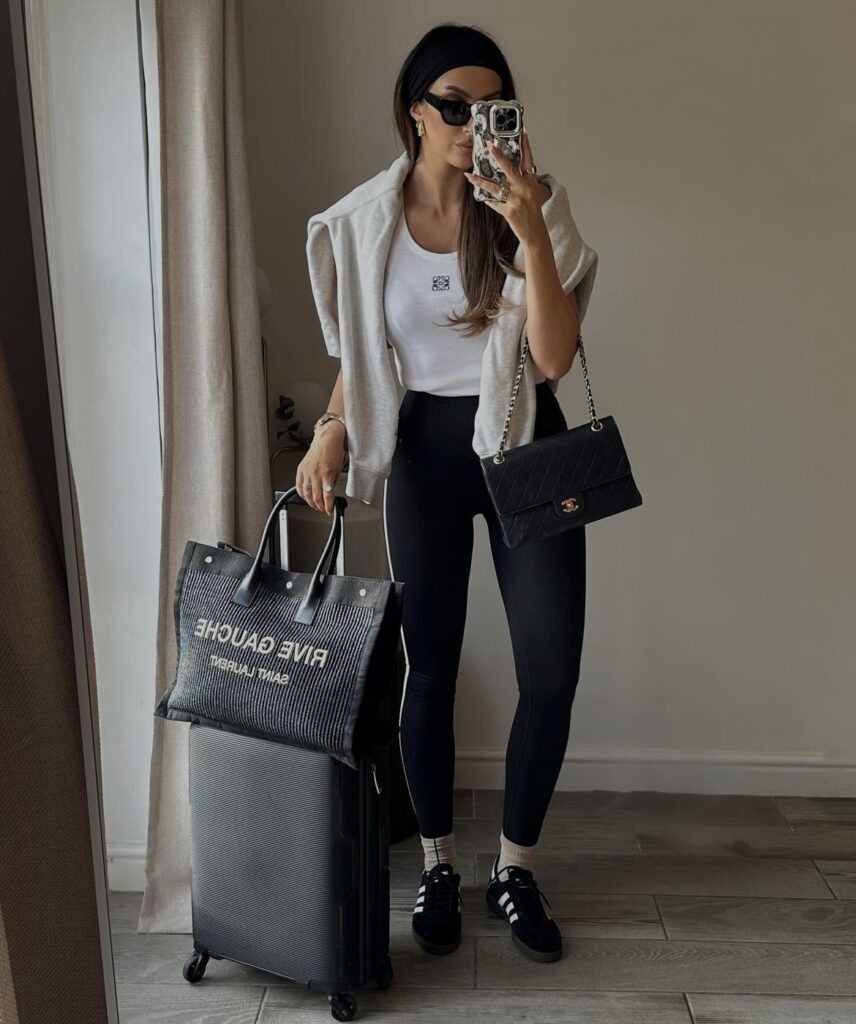 A white tank top, black leggings, and a grey sweatshirt tied around the shoulders, completed with stylish black sneakers and a designer tote.