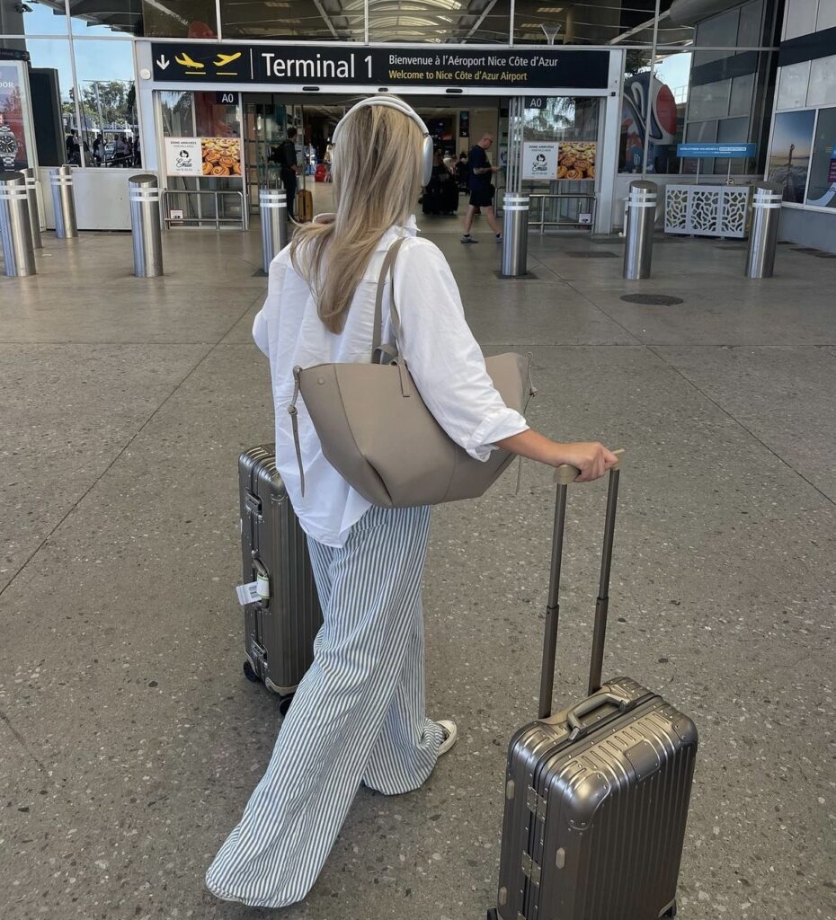 Loose-fitting striped pants and a crisp white blouse, paired with comfortable sneakers and a tote bag.