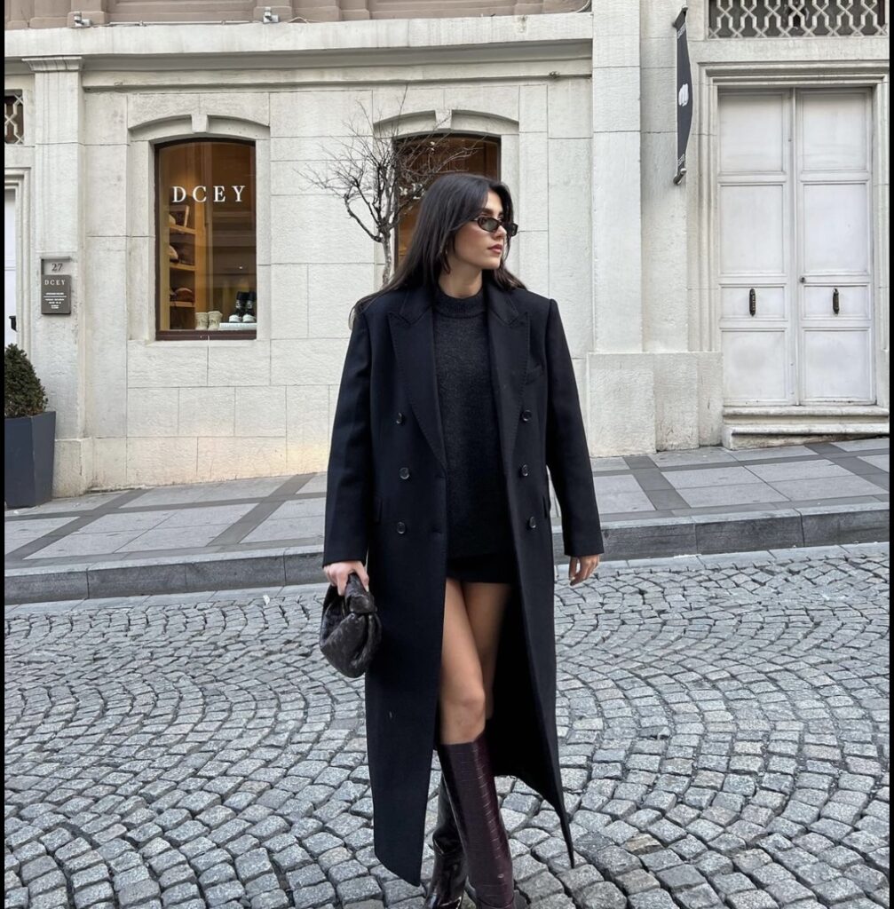 Pair a classic long black coat with a sweater, mini skirt and knee-high boots for a sophisticated outfit.