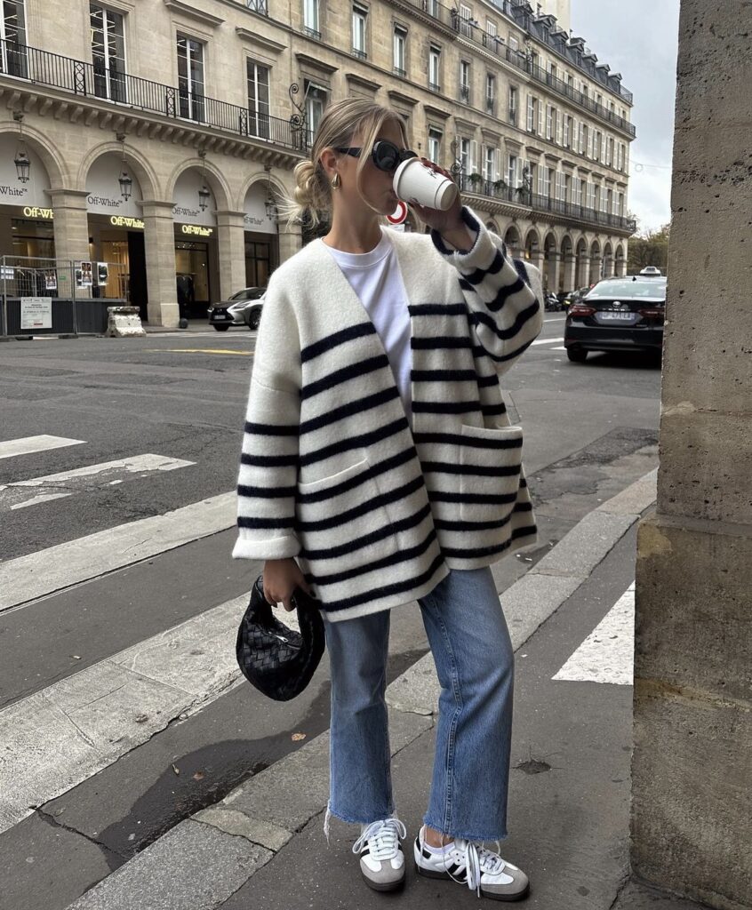 A striped sweater with wide-leg jeans, sneakers, and a chic handbag.