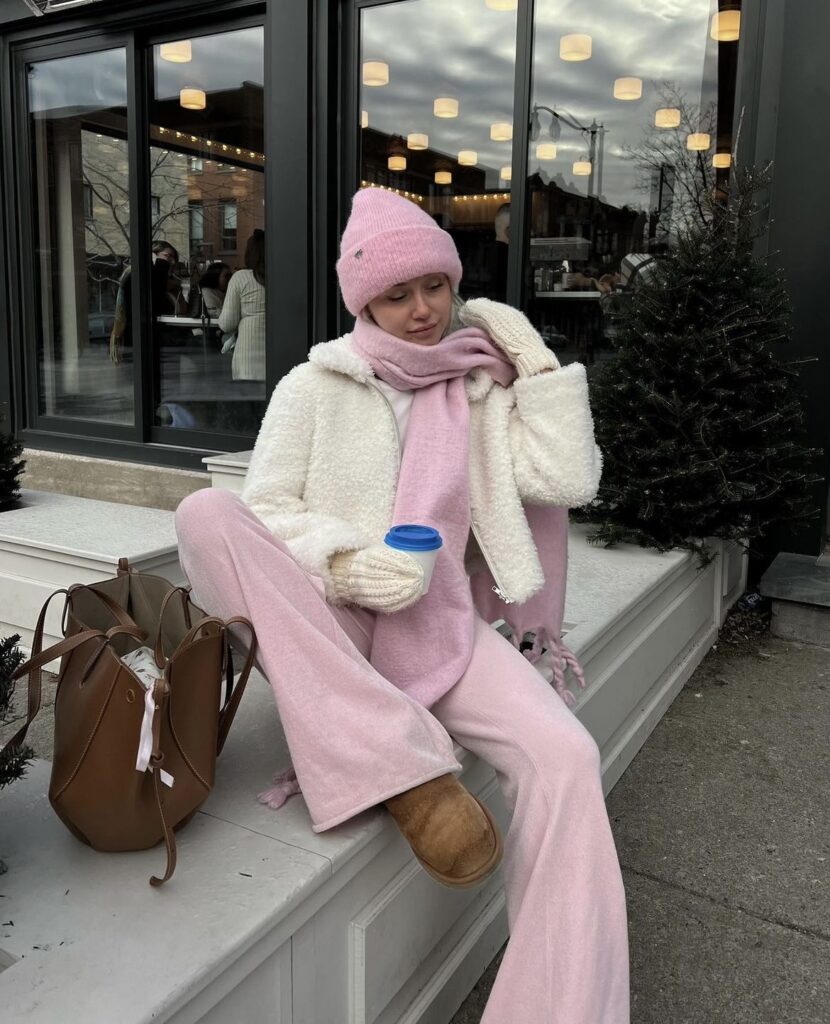 A fluffy white jacket over a pastel pink outfit with a matching beanie and scarf.