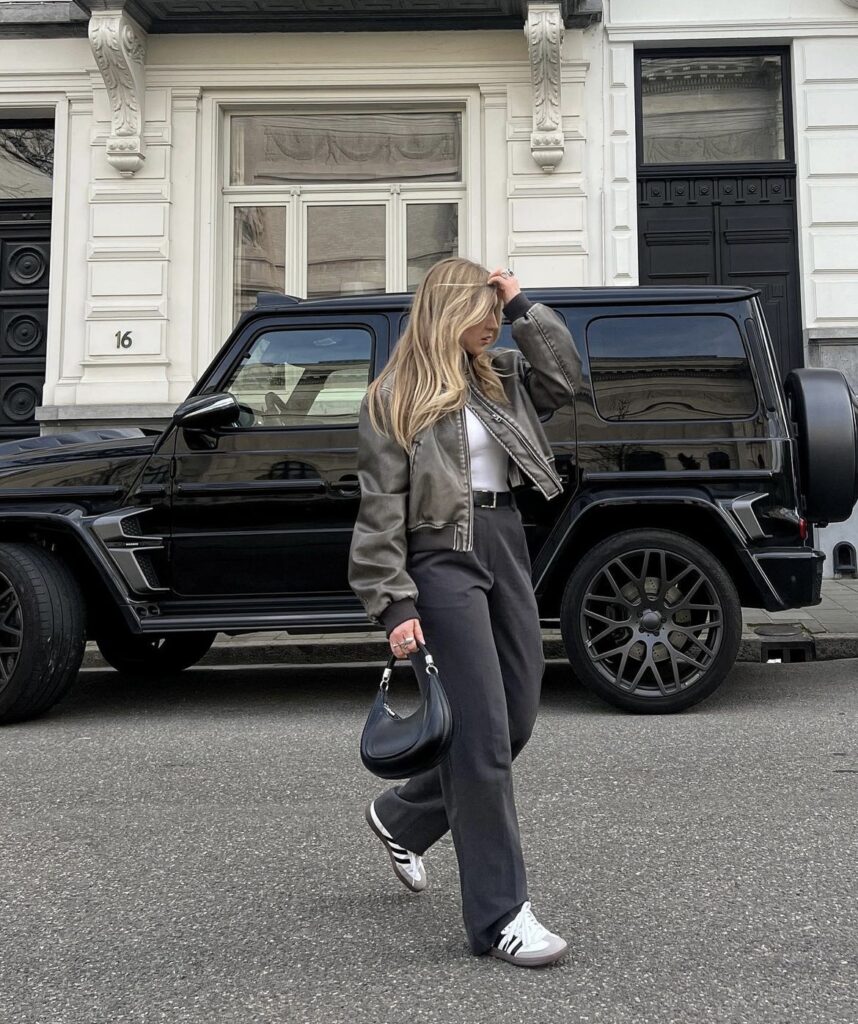 Brown leather jacket with black jeans, white t-shirt, and sneakers for a classic fall look.