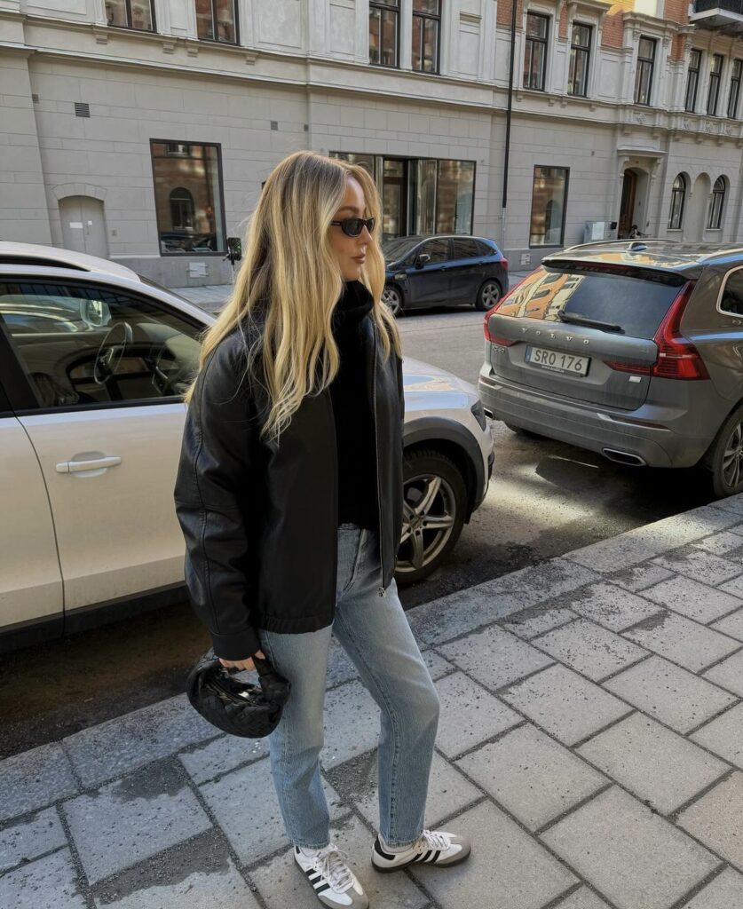 Leather jacket with blue jeans and a black sweater.