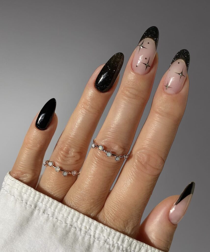 Winter nail design with black nails and sparkling accents, including black French tips.