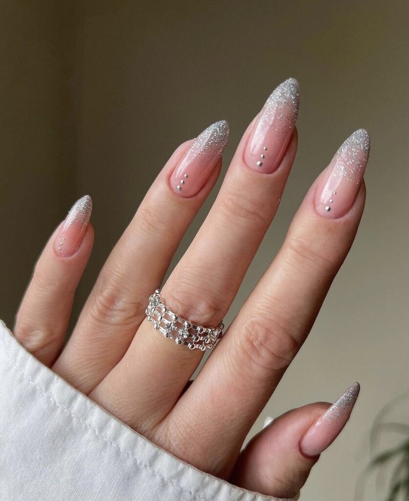 Winter nail design with dazzling silver sparkly tips on a nude base.