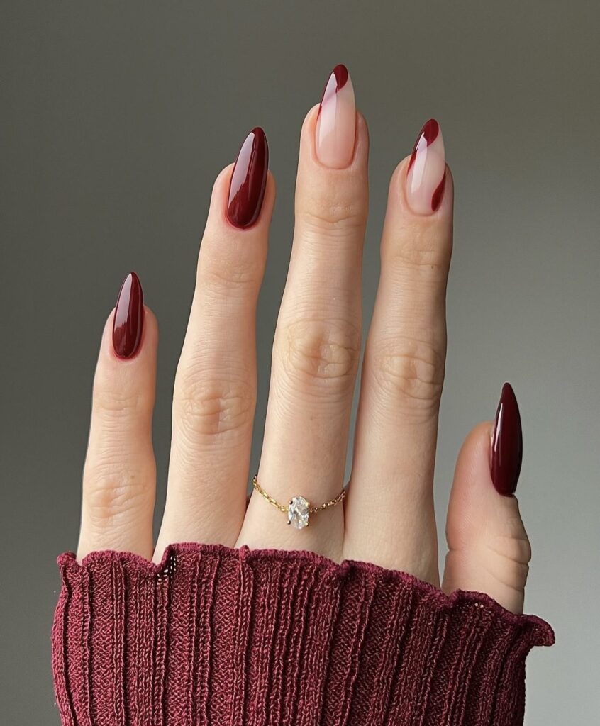 Winter nail design with full burgundy nails and intricate designs on a nude clear base.