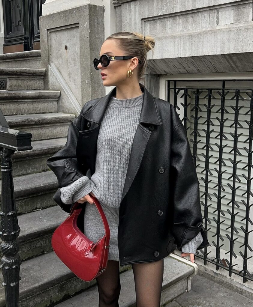 Woman in a cozy sweater dress paired with a leather jacket and knee-high boots.